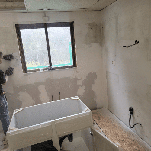 Kitchen renovation in progress with unfinished drywall and new sink installation by Homes by Covenant