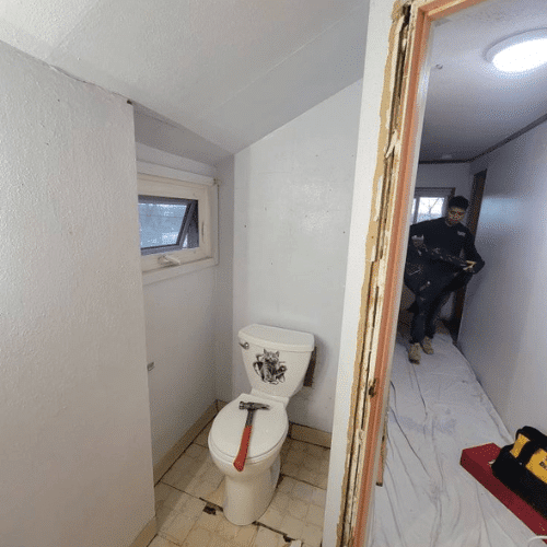 Bathroom update featuring white walls, new flooring, and modern sink installation by Homes by Covenant