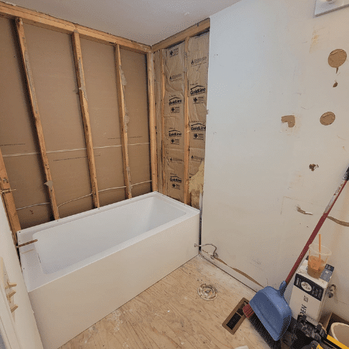Bathroom renovation in framing stage showing new tub installation and wall preparation by Homes by Covenant