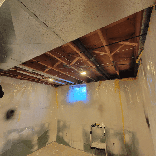 Basement remodeling project with partial drywall installation and ceiling prep by Homes by Covenant