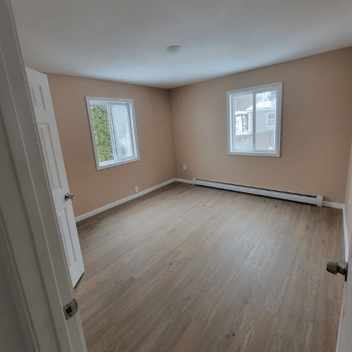Renovated bedroom with new flooring and neutral paint completed by Homes by Covenant