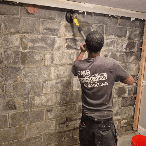Contractor installing stone accent wall as part of basement renovation by Homes by Covenant
