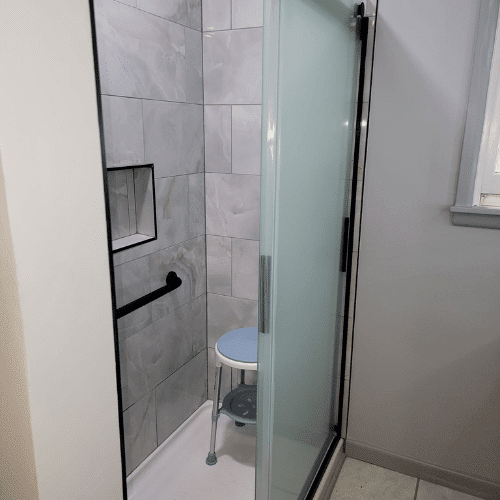 Modern shower remodel with glass door and marble tile installation completed by Homes by Covenant renovation team