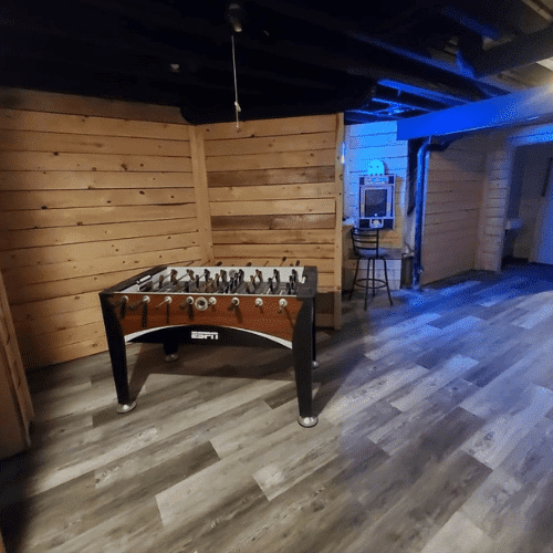 Basement living area with wood walls and flooring finished by Homes by Covenant