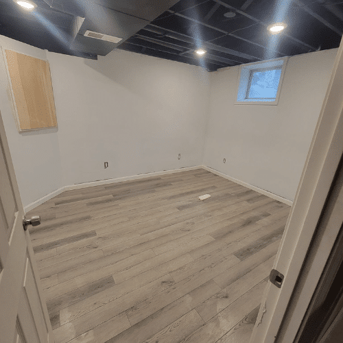 Completed basement remodel with new flooring, lighting, and painted drywall by Homes by Covenant
