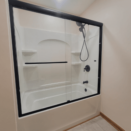 Completed bathroom remodel with white fixtures and black shower trim by Homes by Covenant in Central New York
