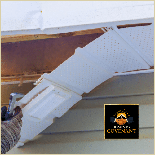 Technician repairing a damaged gutter downspout and soffit area on a residential home exterior.