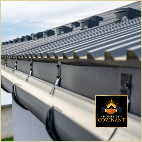 Close-up of a residential gutter system installed under a metal roof, showing brackets, fasteners, and proper drainage alignment.