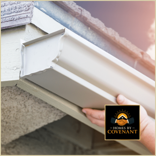 Hands installing a new section of seamless aluminum gutter on a home’s fascia.
