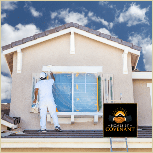 Painter spraying fresh coat on exterior shutters of a home.