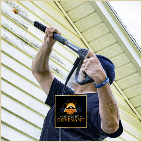 Contractor power washing house siding to prepare for painting.