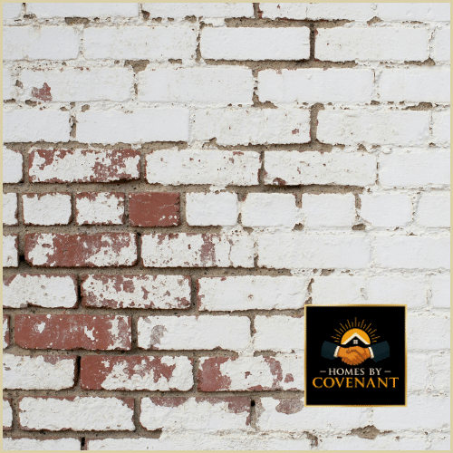 Technician applying waterproof sealant to brick or stone exterior.
