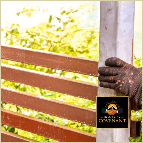 Contractor adjusting metal gate hinges during repair alignment.