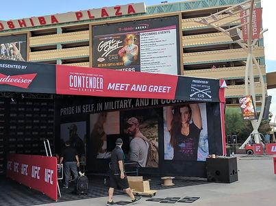 Open-air UFC activation in a city plaza featuring modular structures, banners, and photo walls.