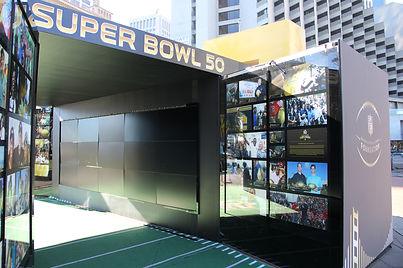 Super Bowl 50 experience tunnel with photo mosaic walls and branded entrance framing.