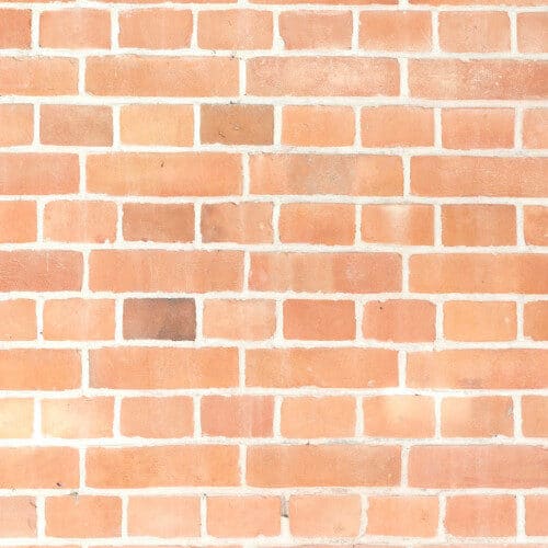 Light red brick masonry wall with uniform rectangular stone pattern.